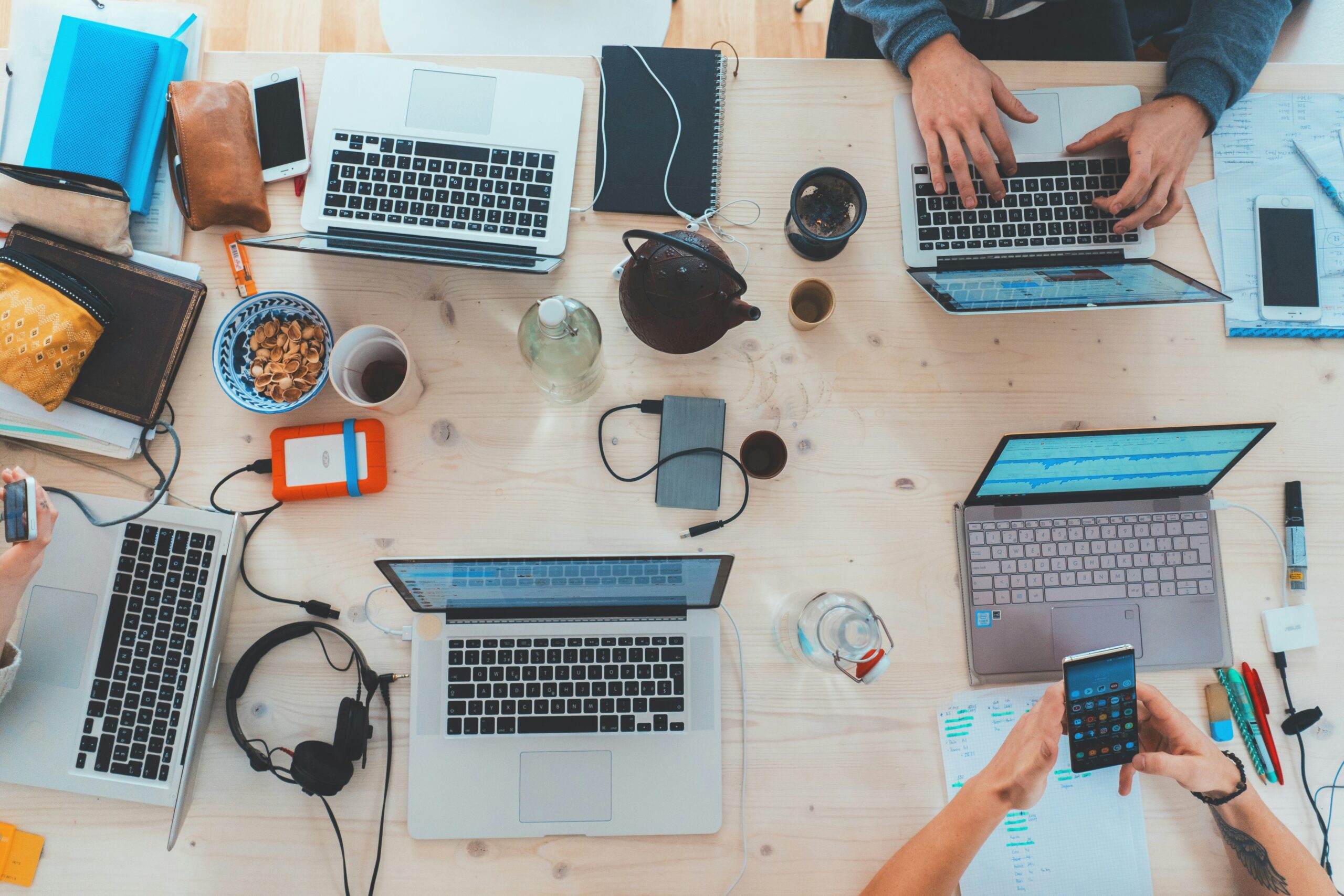 People working at laptops on a desk.