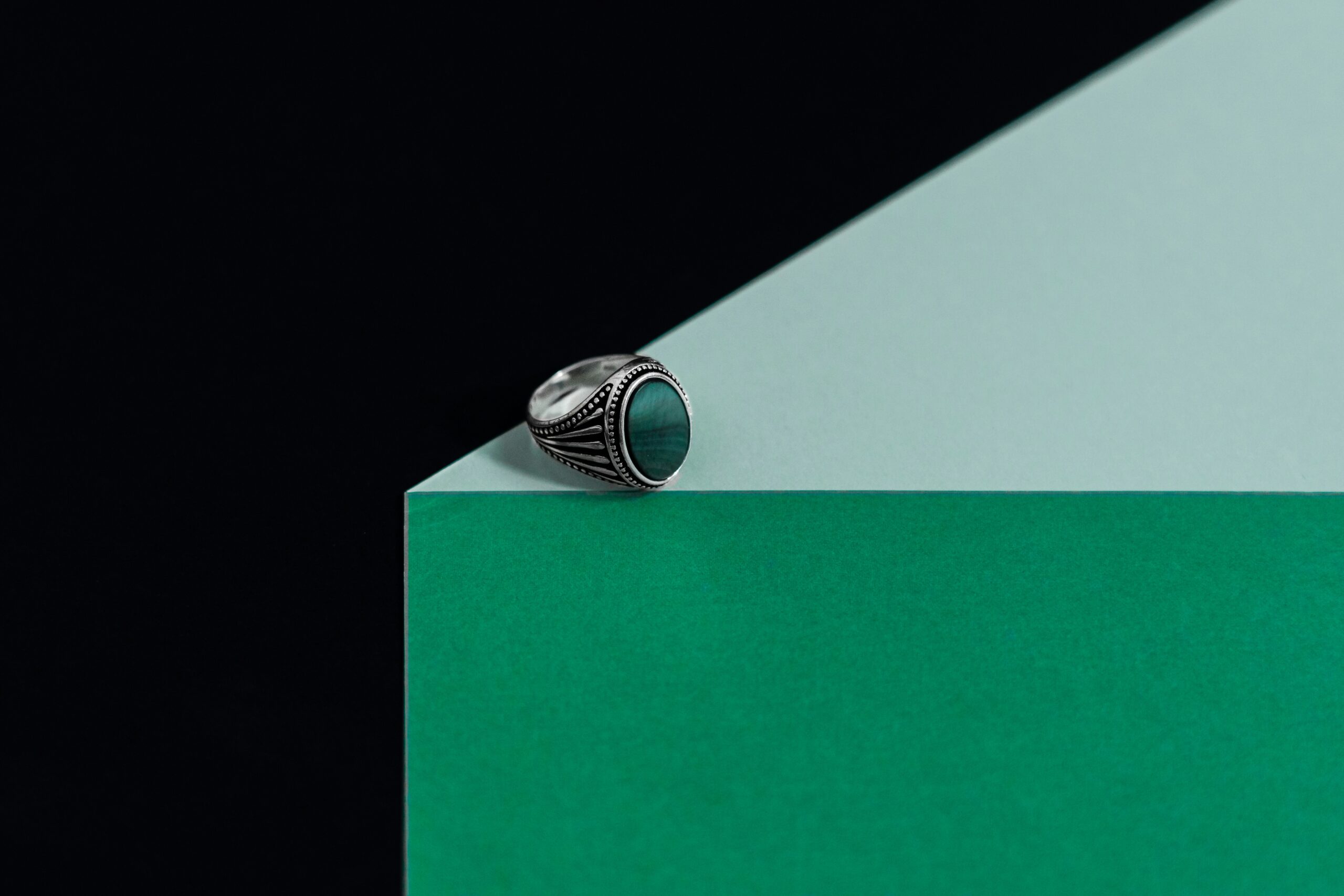 Silver ring on green geometric background